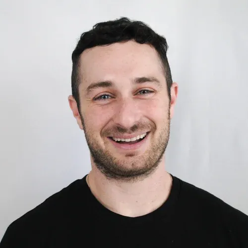 A portrait of Jordan Black, wearing a black shirt and smiling at the camera